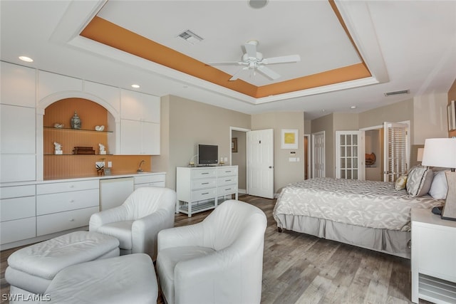 bedroom featuring light hardwood / wood-style floors, ceiling fan, and a raised ceiling