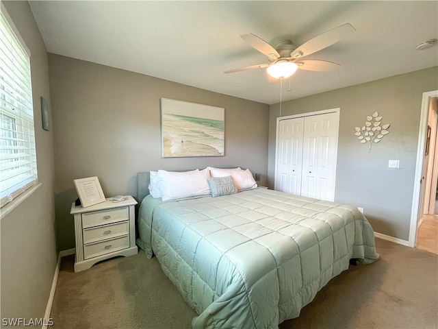 carpeted bedroom featuring a closet, multiple windows, and ceiling fan