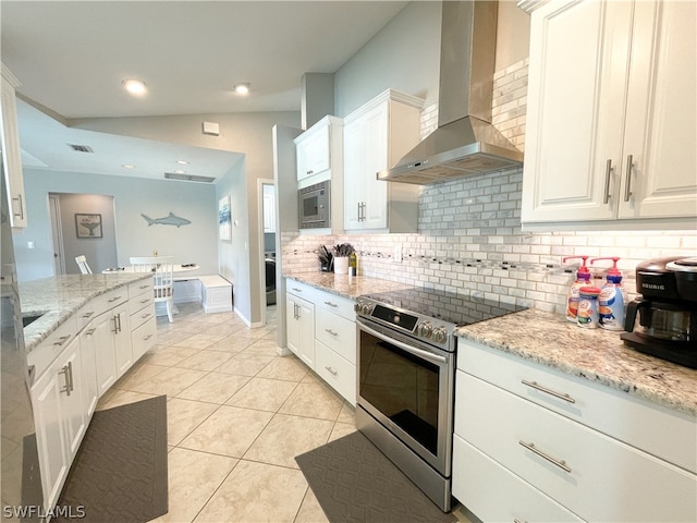 kitchen with appliances with stainless steel finishes, white cabinets, light tile flooring, wall chimney range hood, and tasteful backsplash