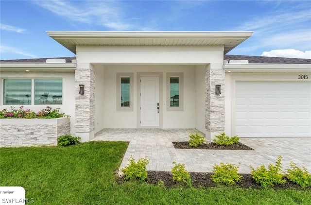 view of exterior entry featuring a yard and a garage