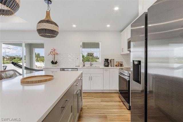 kitchen with white cabinets, light hardwood / wood-style floors, backsplash, and stainless steel appliances