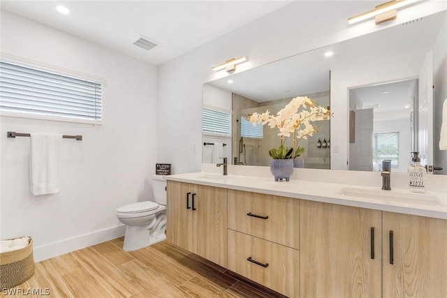 bathroom with a healthy amount of sunlight, toilet, and double vanity