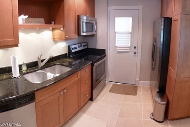 kitchen with light tile patterned floors, appliances with stainless steel finishes, sink, and dark stone counters