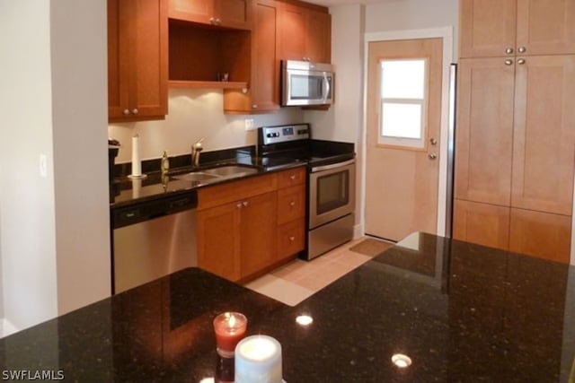 kitchen featuring sink, dark stone counters, and appliances with stainless steel finishes