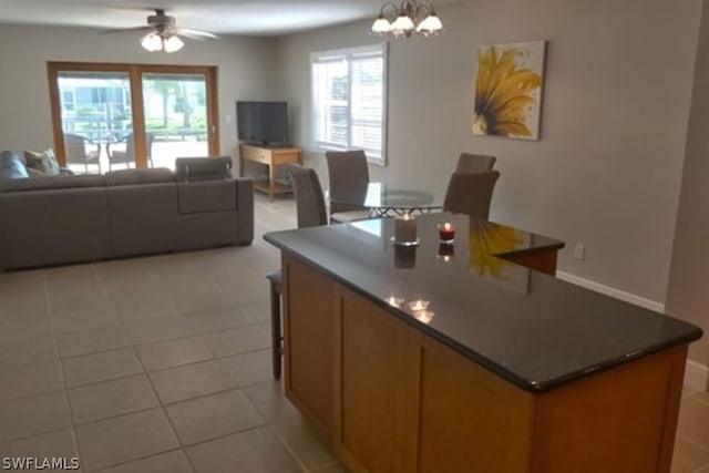 kitchen featuring light tile patterned floors, ceiling fan with notable chandelier, hanging light fixtures, and a center island