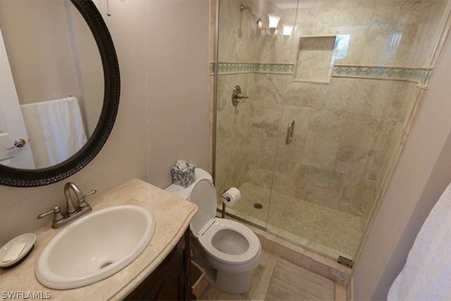 bathroom with tile patterned flooring, vanity, a shower with shower door, and toilet