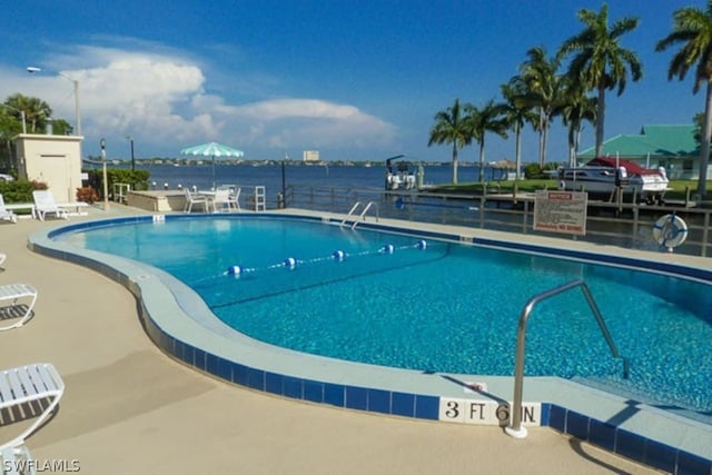 view of swimming pool with a water view and a patio