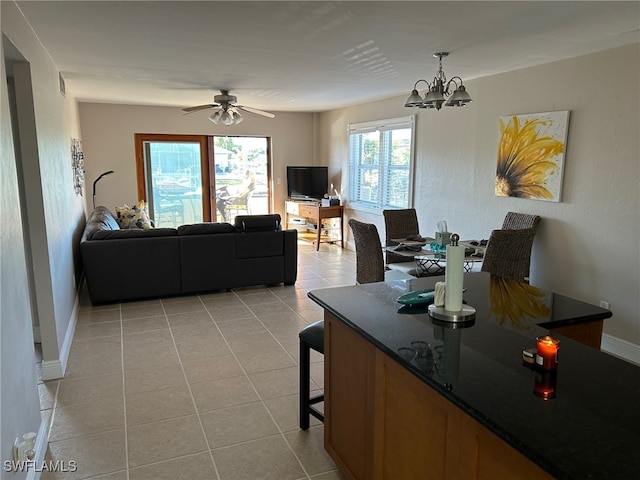 tiled dining space with ceiling fan with notable chandelier