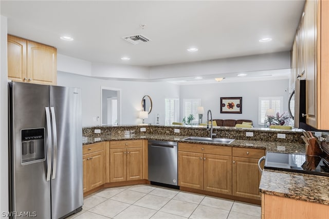 kitchen with light tile patterned flooring, stainless steel appliances, dark stone countertops, and sink