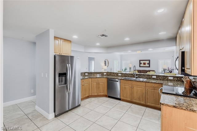 kitchen with sink, light tile patterned floors, stainless steel appliances, and dark stone counters