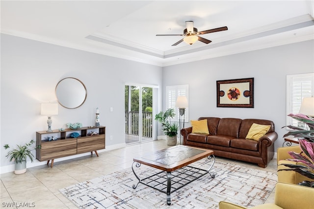 living room featuring light tile patterned floors, ceiling fan, ornamental molding, and a tray ceiling