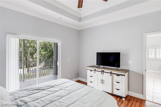 bedroom featuring crown molding, a raised ceiling, hardwood / wood-style flooring, and multiple windows