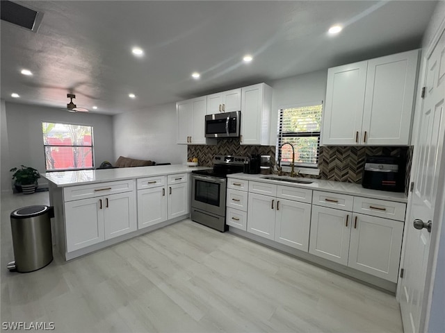 kitchen with sink, appliances with stainless steel finishes, kitchen peninsula, and a healthy amount of sunlight