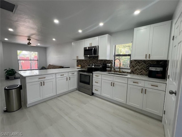 kitchen with a sink, white cabinets, light countertops, appliances with stainless steel finishes, and a wealth of natural light