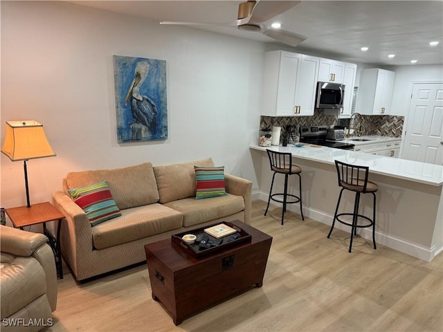 living room with recessed lighting, light wood-style flooring, and baseboards