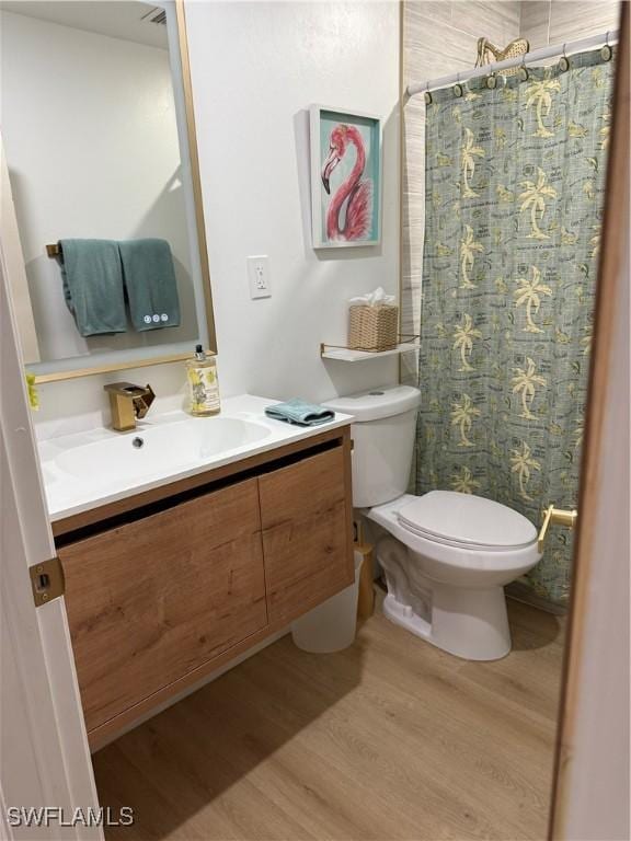 bathroom featuring toilet, a shower with shower curtain, wood finished floors, and vanity