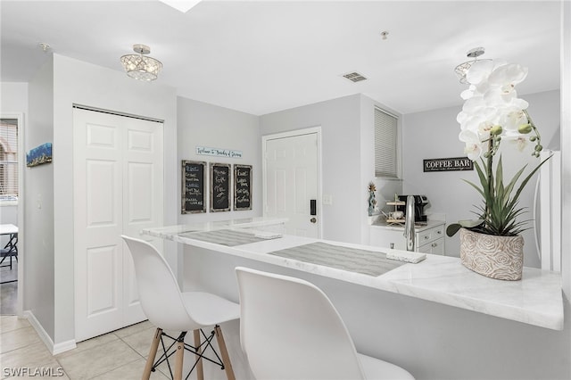 kitchen with light stone countertops, a kitchen bar, and light tile patterned floors