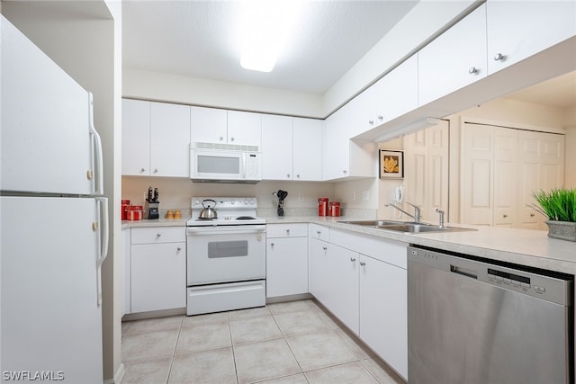 kitchen featuring sink, white appliances, white cabinetry, and light tile floors