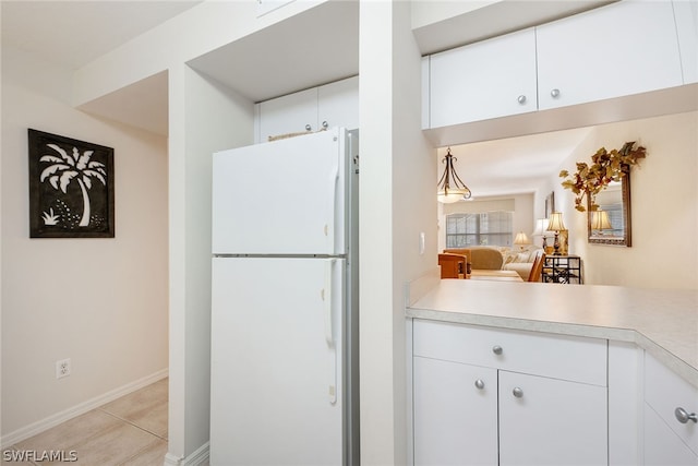 kitchen with white refrigerator, white cabinetry, and light tile floors