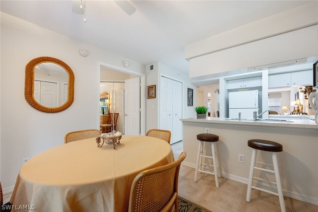 tiled dining room featuring ceiling fan and sink