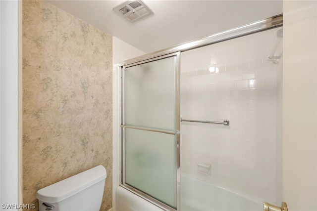 bathroom with enclosed tub / shower combo and toilet