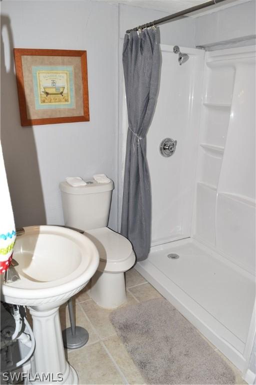 bathroom featuring walk in shower, toilet, and tile flooring