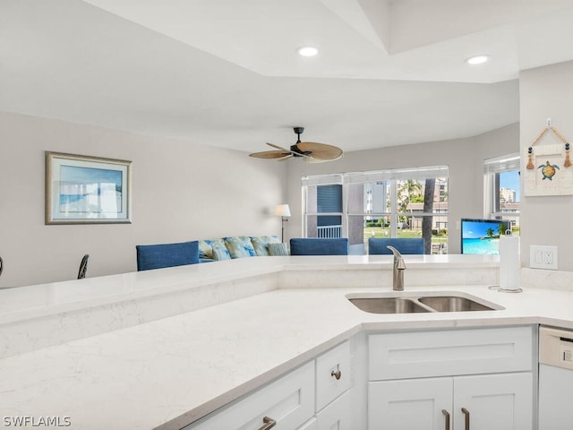 kitchen with white dishwasher, white cabinets, ceiling fan, and sink