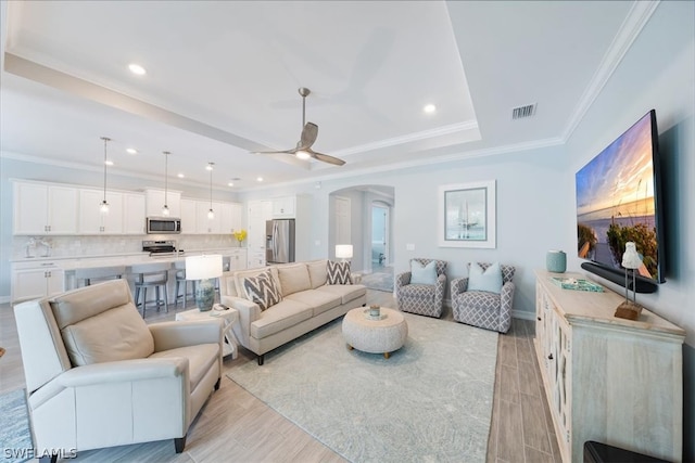 living room featuring light hardwood / wood-style floors, ceiling fan, and ornamental molding