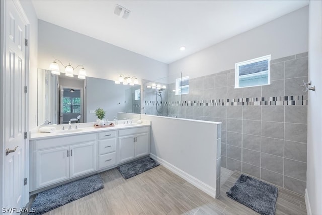 bathroom with hardwood / wood-style flooring, vanity, and tiled shower