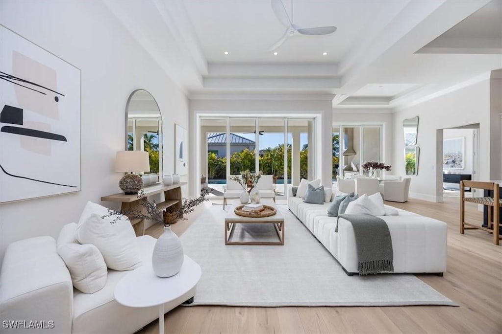 living room featuring a tray ceiling, ceiling fan, and light hardwood / wood-style floors