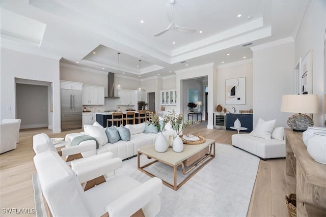 living room featuring a raised ceiling, wine cooler, ceiling fan, and light hardwood / wood-style flooring