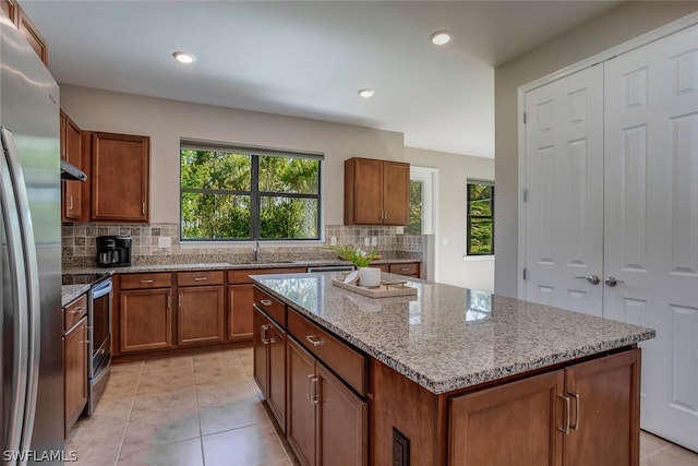 kitchen with light stone countertops, tasteful backsplash, appliances with stainless steel finishes, and a center island