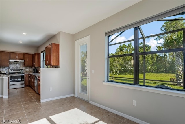 kitchen with stainless steel appliances, a wealth of natural light, light tile patterned floors, and backsplash