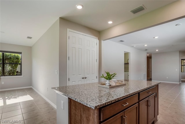 kitchen featuring light stone countertops, light tile patterned floors, and a kitchen island