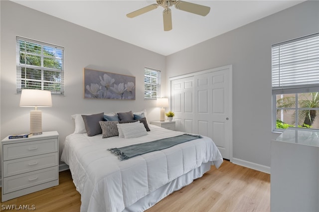 bedroom featuring a closet, multiple windows, ceiling fan, and light wood-type flooring