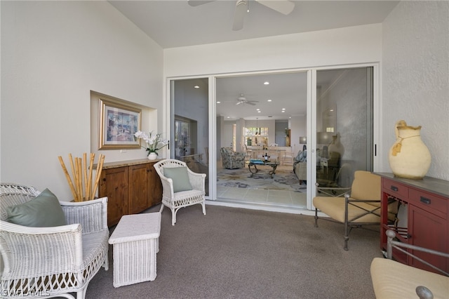 sitting room with dark colored carpet and ceiling fan