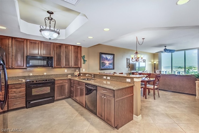 kitchen featuring kitchen peninsula, stone counters, hanging light fixtures, and black appliances