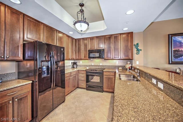 kitchen with stone counters, light tile floors, black appliances, sink, and a raised ceiling