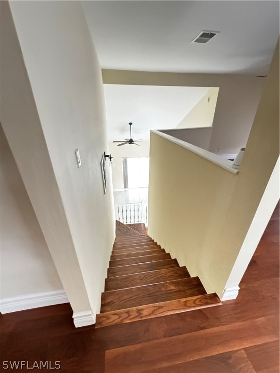 stairway with hardwood / wood-style floors and ceiling fan