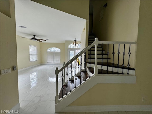 staircase with ceiling fan with notable chandelier