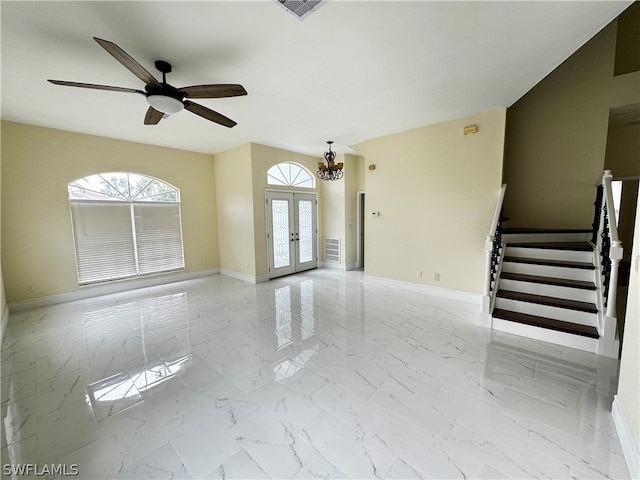 empty room with french doors and ceiling fan with notable chandelier