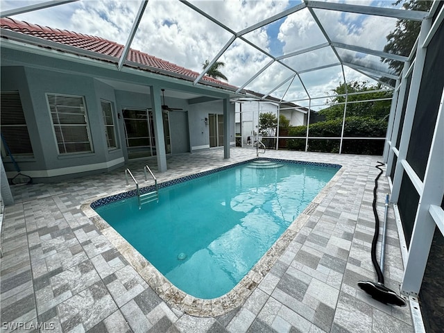 view of swimming pool with a patio, glass enclosure, and ceiling fan