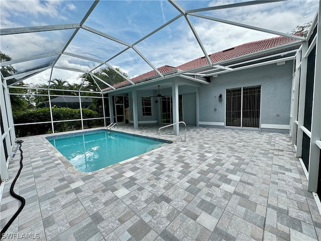 view of swimming pool with a patio, glass enclosure, and ceiling fan