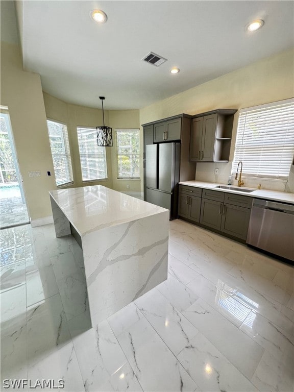 kitchen with appliances with stainless steel finishes, hanging light fixtures, a healthy amount of sunlight, and sink