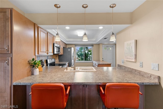 kitchen featuring backsplash, a raised ceiling, stainless steel appliances, kitchen peninsula, and pendant lighting