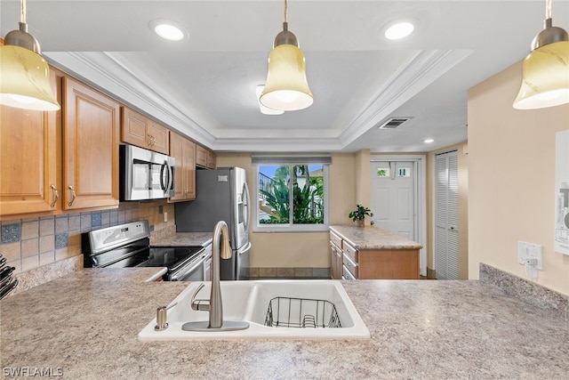 kitchen with pendant lighting, crown molding, backsplash, appliances with stainless steel finishes, and a raised ceiling