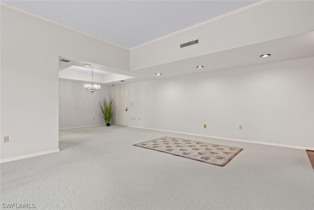 carpeted empty room featuring a raised ceiling, crown molding, and a notable chandelier