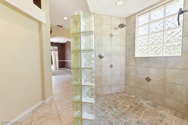 bathroom with tile floors, a healthy amount of sunlight, and a tile shower