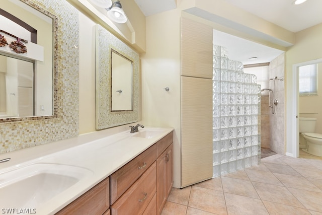 bathroom featuring double vanity, tiled shower, tile floors, and toilet