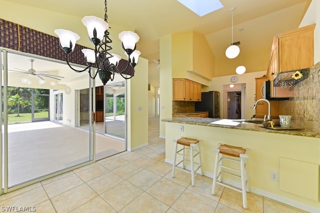 kitchen featuring a skylight, tasteful backsplash, pendant lighting, and kitchen peninsula